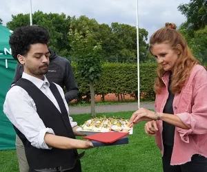 männliche Servicekraft des Catering dienstleisters Opitz mit Fingerfood auf einem Tablett und einer weiblichen Kundin 